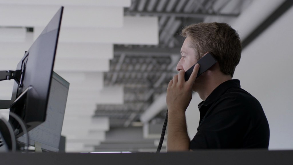 Photo of David Ward at a computer on the phone with a client